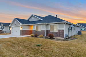 View of front of home with brick siding, a yard, and a garage