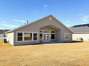 Back of property featuring stucco siding, a patio, french doors, and a lawn