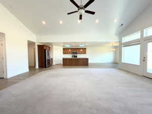 Unfurnished living room with lofted ceiling, ceiling fan, recessed lighting, and light colored carpet