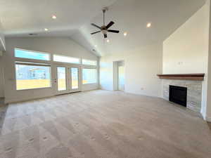 Unfurnished living room featuring a high ceiling, ceiling fan, a fireplace, recessed lighting, and light colored carpet