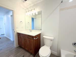 Bathroom featuring vanity, dark wood-style flooring, and shower / bathtub combination