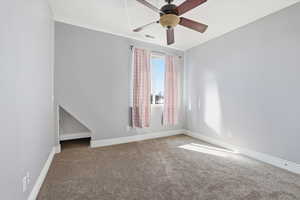 Carpeted empty room featuring baseboards and ceiling fan