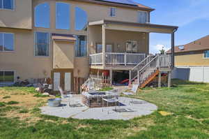 Rear view of property with a patio, stucco siding, an outdoor fire pit, and a wooden deck