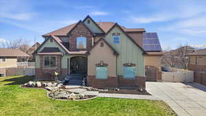 View of front facade featuring a gate, roof with shingles, roof mounted solar panels, concrete driveway, and a garage