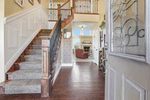 Entrance foyer featuring dark wood finished floors, a lit fireplace, and a high ceiling