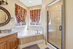 Bathroom featuring a marble finish shower, vanity, a tub with jets, light tile patterned flooring, and recessed lighting