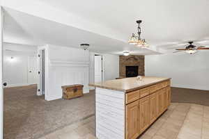 Kitchen with light carpet, a center island, a stone fireplace, open floor plan, and light countertops