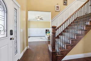 Entryway with a decorative wall, dark wood-type flooring, wainscoting, a ceiling fan, and crown molding