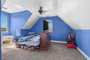 Carpeted bedroom featuring ceiling fan and a textured ceiling