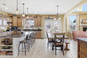 Kitchen featuring open shelves, dark stone countertops, wood finish cabinetry, a kitchen breakfast bar, and a center island