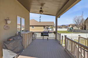 Wooden deck with a playground, ceiling fan, a residential view, and area for grilling