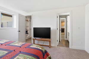 Bedroom with light carpet and a walk in closet