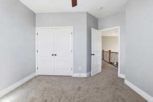 Unfurnished bedroom featuring light colored carpet, a closet, and ceiling fan