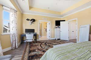 Bedroom with a desk, crown molding, a tray ceiling, and dark wood-style floors