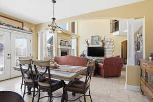 Dining room with arched walkways, french doors, a fireplace, light tile patterned floors, and suspended lighting