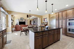 Kitchen featuring dark stone counters, double oven, arched walkways, and open floor plan