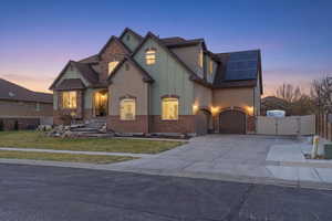 Craftsman-style house with a gate, roof mounted solar panels, concrete driveway, and stucco siding