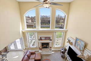 Carpeted living area featuring a fireplace, healthy amount of natural light, and a high ceiling
