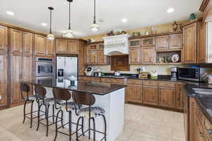 Kitchen with a kitchen breakfast bar, dark stone counters, wood finish cabinets, open shelves, and stainless steel appliances