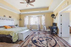 Bedroom featuring crown molding, a tray ceiling, and a ceiling fan