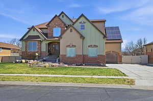 Craftsman-style house featuring a gate, roof mounted solar panels, driveway, board and batten siding, and brick siding