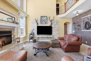 Living room with arched walkways, a fireplace, and a high ceiling