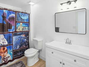 Full bath featuring vanity, curtained shower, and light wood-style flooring