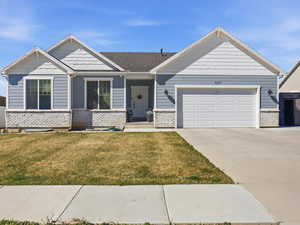 Craftsman house with a front lawn, driveway, an attached garage, and brick siding