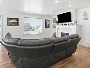 Living area with light wood-type flooring, a glass covered fireplace, and recessed lighting