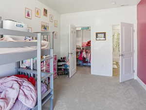 Bedroom featuring a spacious closet and light colored carpet