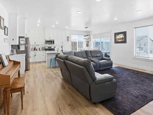 Living room with light wood finished floors and suspended lighting
