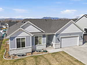 View of front of house with an attached garage, concrete driveway, a front lawn, a shingled roof, and brick siding