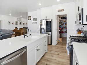 Kitchen featuring white cabinets, stainless steel appliances, light wood-style flooring, open floor plan, and recessed lighting