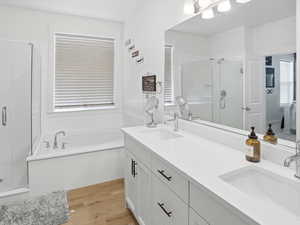 Bathroom with a stall shower, a bath, double vanity, and light wood finished floors