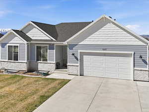 Craftsman house with a front lawn, driveway, an attached garage, brick siding, and roof with shingles