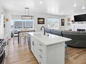 Kitchen with open floor plan, a breakfast bar area, white cabinetry, and light wood finished floors