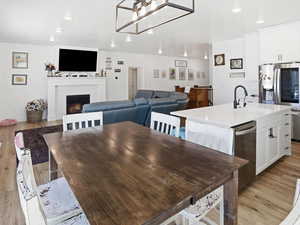 Dining space featuring light wood finished floors, a lit fireplace, and recessed lighting