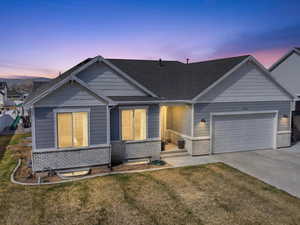 View of front of house with brick siding, a garage, a front yard, concrete driveway, and roof with shingles
