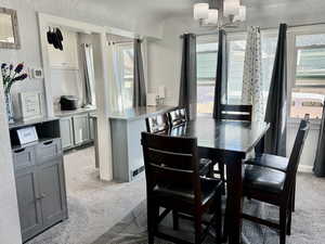 Dining space featuring a textured wall, light colored carpet, and suspended lighting