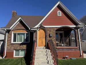 View of front of house with a chimney, brick siding, and a shingled roof