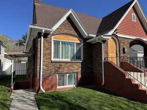 View of front of home with brick siding, a shingled roof, a chimney, and a front yard