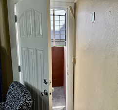 Doorway to outside with a textured wall and unfinished concrete flooring