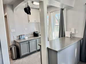 Kitchen featuring a textured wall, stainless steel counters, light carpet, and dual tone cabinets