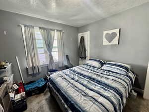 Bedroom with dark carpet and a textured ceiling