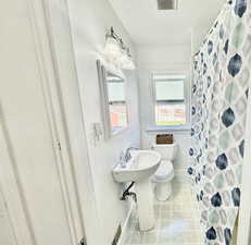 Bathroom with curtained shower, a textured ceiling, and light tile patterned flooring
