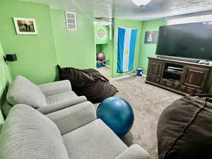 Living area with light colored carpet and a textured ceiling