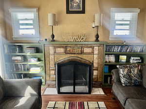 Sitting room with a textured wall, a tile fireplace, and wood finished floors