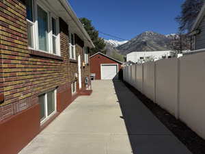 View of property exterior featuring brick siding, a garage, a mountain view, driveway, and an outbuilding
