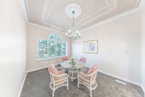 Dining area with dark carpet, a chandelier, and crown molding
