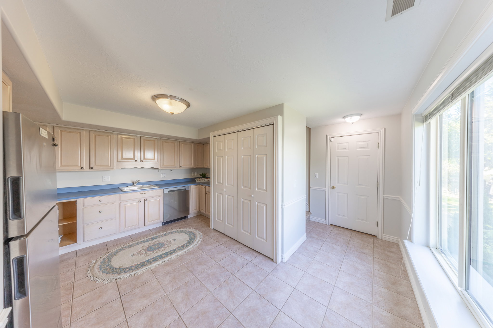 Kitchen with stainless steel appliances, light wood finish cabinets, light tile patterned flooring, and light countertops